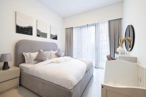 una camera da letto bianca con un letto grande e uno specchio di EMAAR GRANDE - Elegant 1 Bedroom Apartment - Infinity Pool - 1min to Dubai Mall and Burj Khalifa a Dubai