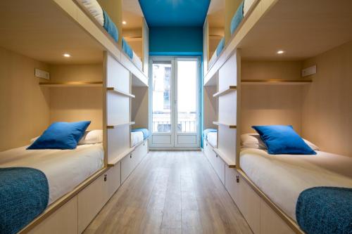 two beds in a room with open shelves at Mola Hostel in Madrid