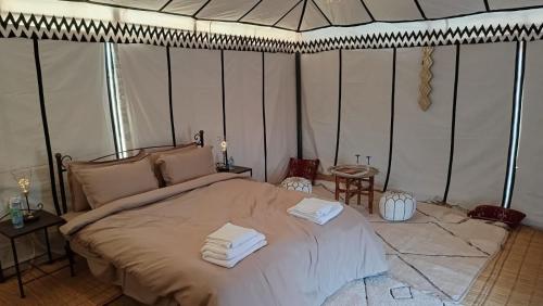 a bedroom with a large bed with towels on it at Akwabir camp in El Gouera