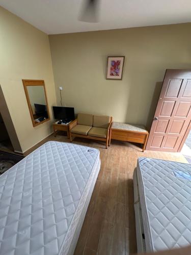 a bedroom with two beds and a living room with a couch at Santai Salai Homestay and Cafe in Kepala Batas