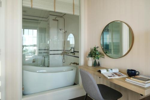 Un baño con bañera, lavabo y espejo. en Charming Beachfront Retreat, Minutes from Pattaya, en Na Jomtien