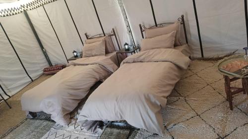 a bedroom with two beds with white comforters at Akwabir camp in El Gouera