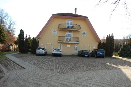a large yellow building with cars parked in a driveway at 4 You Apartmans in Egerszalók