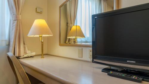 a flat screen tv sitting on a table with a lamp at Taira View Hotel in Iwaki