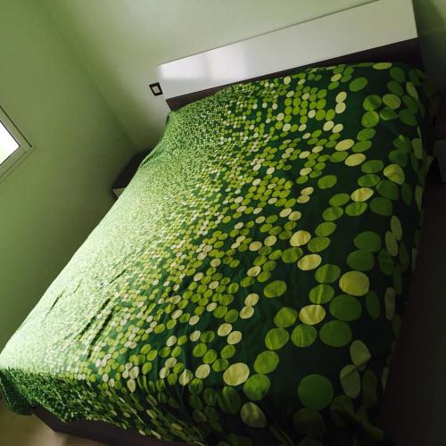a bed with a green comforter on top of it at Alcudia Smir in Fnidek