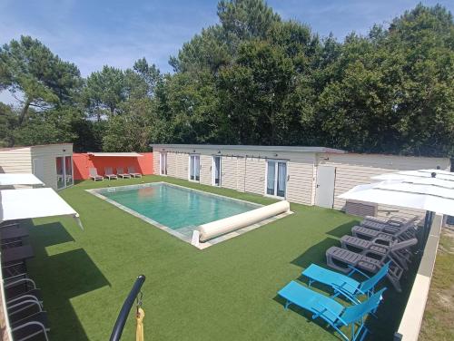 une grande arrière-cour avec une piscine, des chaises et des parasols dans l'établissement VILLA piscine-spa-sauna, 25 personnes, 5 mn océan, à Soulac-sur-Mer