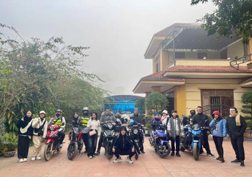 a group of people posing for a picture with their motorcycles at Wind's House Ha Giang in Ha Giang