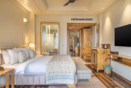 a bedroom with a large bed and a flat screen tv at Echor Mandara TreeVilla Dharamshala in Dharamshala