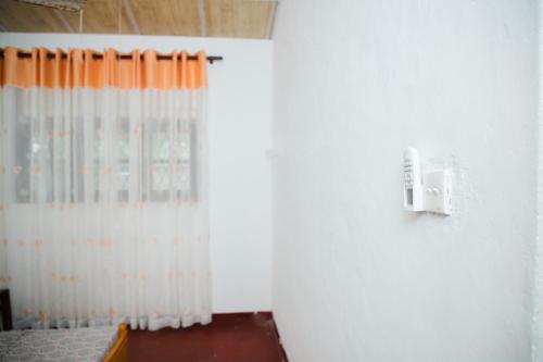 a room with a white and orange shower curtain at Surf Hostel Hiriketiya in Dickwella