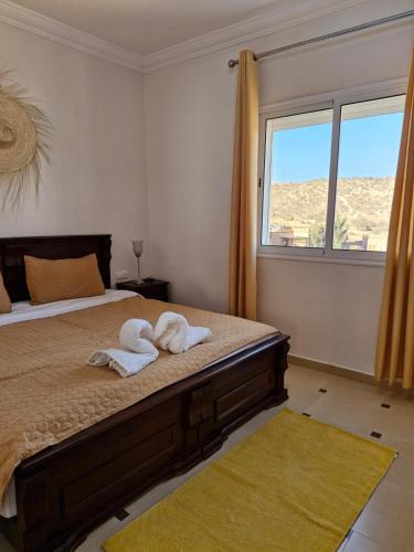 a bedroom with towels on a bed with a window at SINIM HOUSE in Taghazout