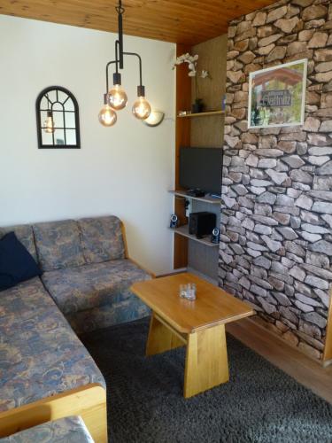 a living room with a couch and a stone wall at Ferienhaus Schäfer - Apartments - Wintersports - Family holiday - Holiday with your dog - Rural & Scenic in Flattnitz
