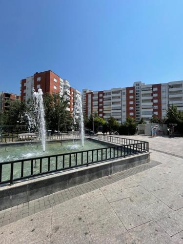 a fountain in a park with buildings in the background at Cozy Apartment in Gjilan in Gjilan