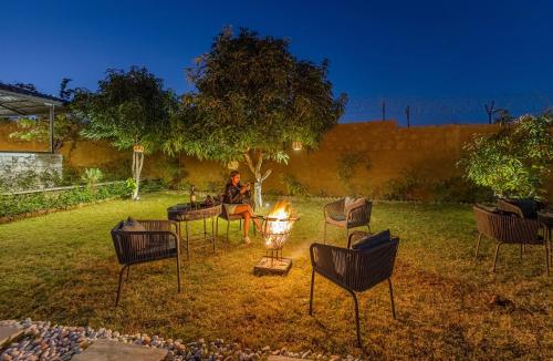 DebāriELIVAAS Cows & Cuddles 4 BHK with Pvt Pool and Garden的坐在院子火旁的女人