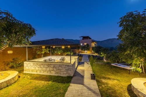 a backyard of a house with a stone fountain at ELIVAAS Cows & Cuddles 4 BHK with Pvt Pool and Garden in Debāri