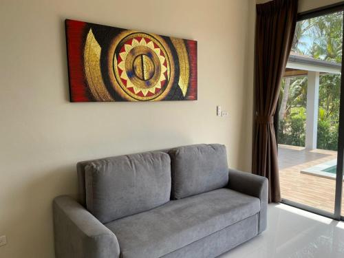 a couch in a living room with a painting on the wall at Mirari Villa in Koh Phangan