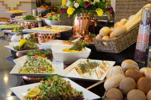 a buffet with plates of food on a table at Cassia Hotel Jerusalem in Jerusalem