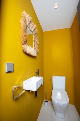 La salle de bains jaune est pourvue de toilettes et d'un miroir. dans l'établissement Cocon luxe vue balcon sauna jacuzzi piscine, à Villeneuve-lès-Avignon