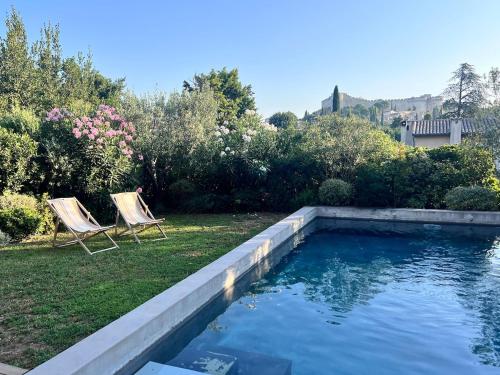 - une piscine avec deux chaises dans la cour dans l'établissement Cocon luxe vue balcon sauna jacuzzi piscine, à Villeneuve-lès-Avignon