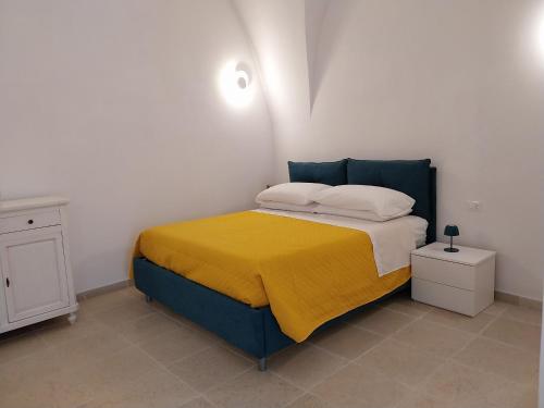 a bedroom with a bed with a yellow blanket on it at Casa Antonietta - Ostuni Centro in Ostuni