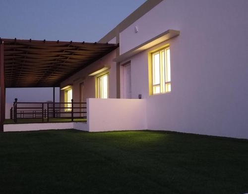 a white house with windows and a green lawn at Luban Camping House in Bidiyah