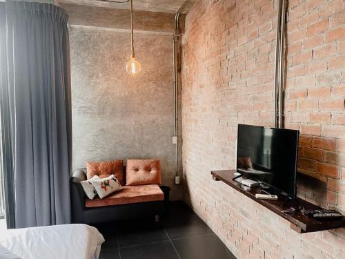 a room with a couch and a tv and a brick wall at The LOCAL Ari in Bangkok