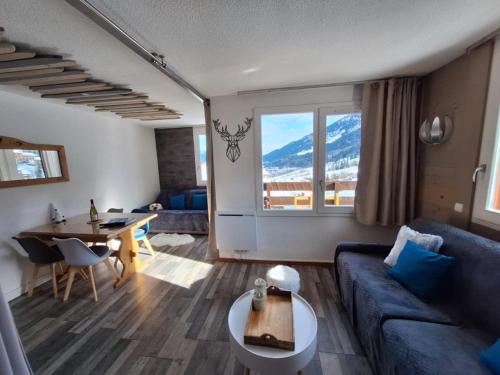 un salon avec un canapé bleu et une table dans l'établissement La Casa Di Giuma Magnifique studio à Valmorel, à Valmorel
