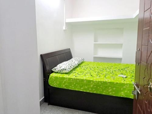 a bedroom with a bed with a green sheet and a pillow at Airport PickupBeachChepauk StadiumKitchenWIFI in Chennai