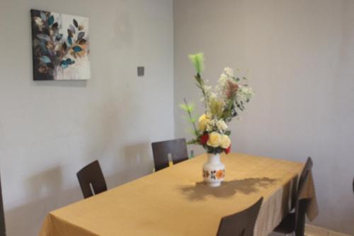 a table with a vase of flowers on it at Green house, 2bdr Apt, 7 min from Airport in Accra
