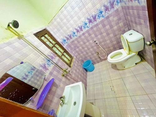 Baño alicatado de color rosa con aseo y lavamanos en Venus Guest House, en Hyderabad