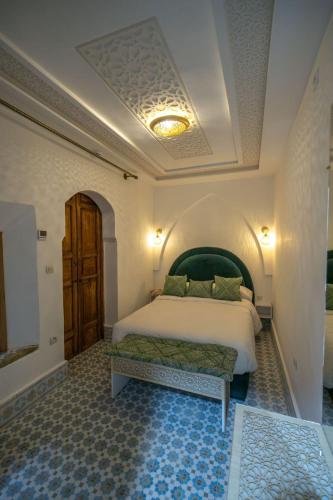 a bedroom with a bed with a green headboard at Dar Mima in Fès