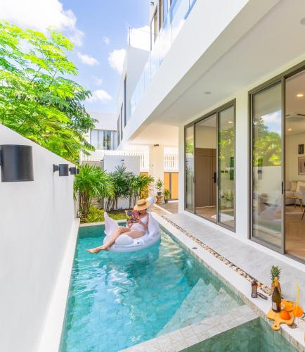 a woman is sitting on a raft in a pool in a house at Manima Luxury Pool Villa - Bangtao in Phuket