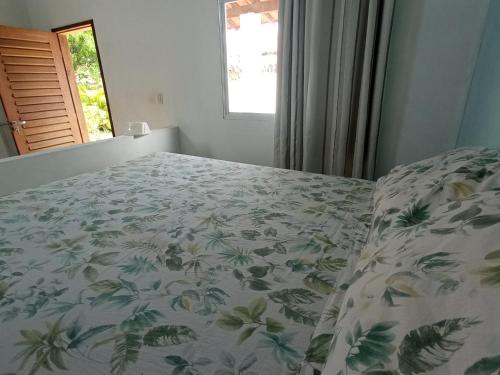 a bedroom with a bed with a floral bedspread at Casa INTI de Maracajaú in Maracajaú