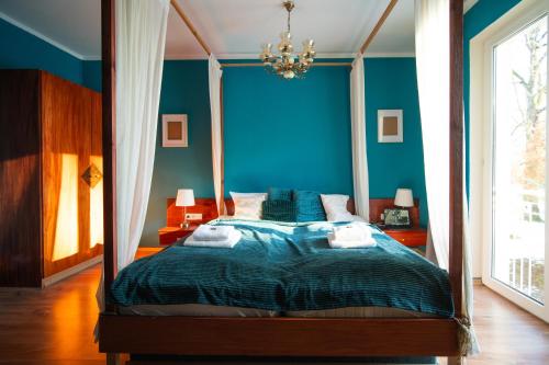 a bedroom with a canopy bed with blue walls at Berghotel Drei Brüder Höhe in Marienberg