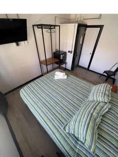 a large bed with striped sheets and a chair at VOY Hostales - 4 Norte in Viña del Mar