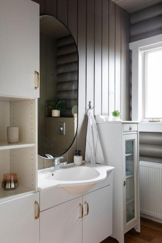 a bathroom with a white sink and a mirror at The Eyrie - Luxurious Cabin in the Golden Circle in Úthlid