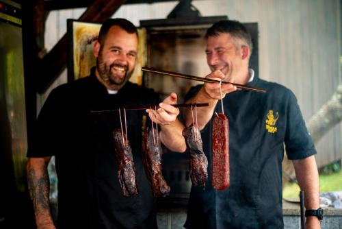 two men are holding skewers with meat on chopsticks at Spa Hotel Diana in Františkovy Lázně