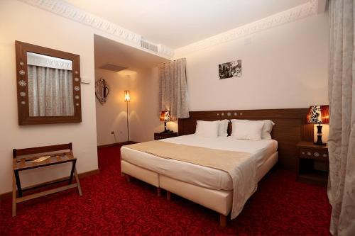 a bedroom with a large bed and a red carpet at Le Caid Hotel in Bou Saâda
