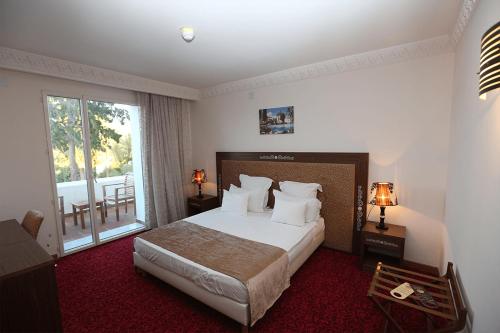 a hotel room with a bed and a balcony at Le Caid Hotel in Bou Saâda