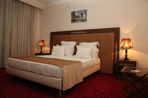 a hotel room with a large bed with white pillows at Le Caid Hotel in Bou Saâda