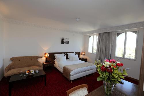 a hotel room with a bed and a couch at Le Caid Hotel in Bou Saâda