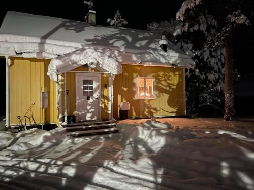 a small yellow house with snow on it at Mysigt hus på hästgård, mellan Jukkasjärvi och Kiruna in Kiruna