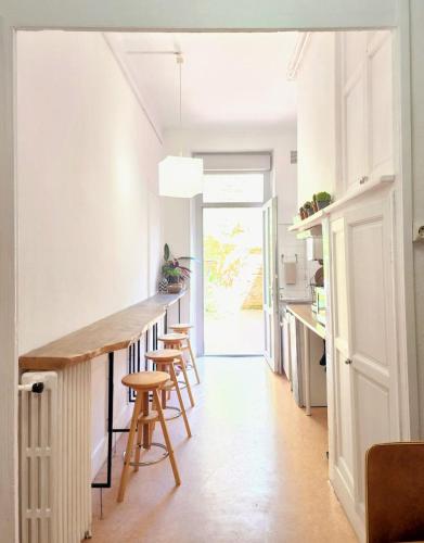 une cuisine avec des murs blancs et un comptoir avec des tabourets dans l'établissement Zen rustic home & private backyard Toulouse center, à Toulouse