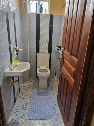 a bathroom with a toilet and a sink and a door at D & C Homes in Eldoret