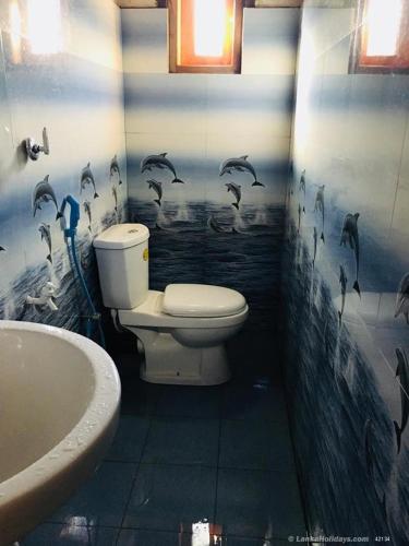 Ein Badezimmer mit Toilette und an die Wand gemalten Delfinen. in der Unterkunft Subhasinghe guest in Ella