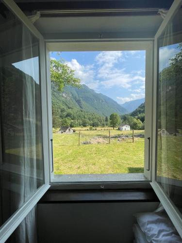 a window with a view of a field and mountains at Casa Sonia Your Refuge in Valle Verzasca in Frasco