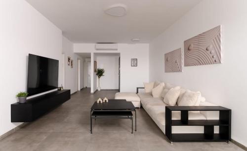 a living room with a white couch and a tv at Stunning and spacious in Kiryat Ata in Qiryat Ata