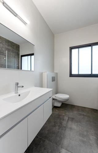 a white bathroom with a sink and a toilet at Stunning and spacious in Kiryat Ata in Qiryat Ata