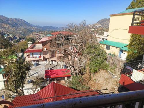 a group of buildings on a hill with red roofs at Aashiyana Studio Homestay in Solan