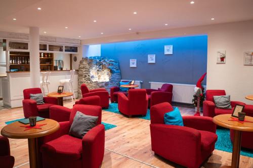 a waiting room with red chairs and tables at Berghotel Drei Brüder Höhe in Marienberg