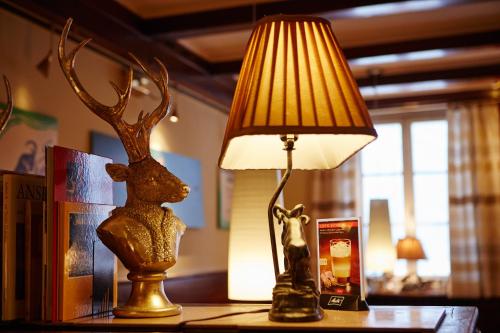 a table with a lamp and a statue of a deer on it at Boutique Hotel & Bio Wirtshaus Schwarzer Bock in Ansbach
